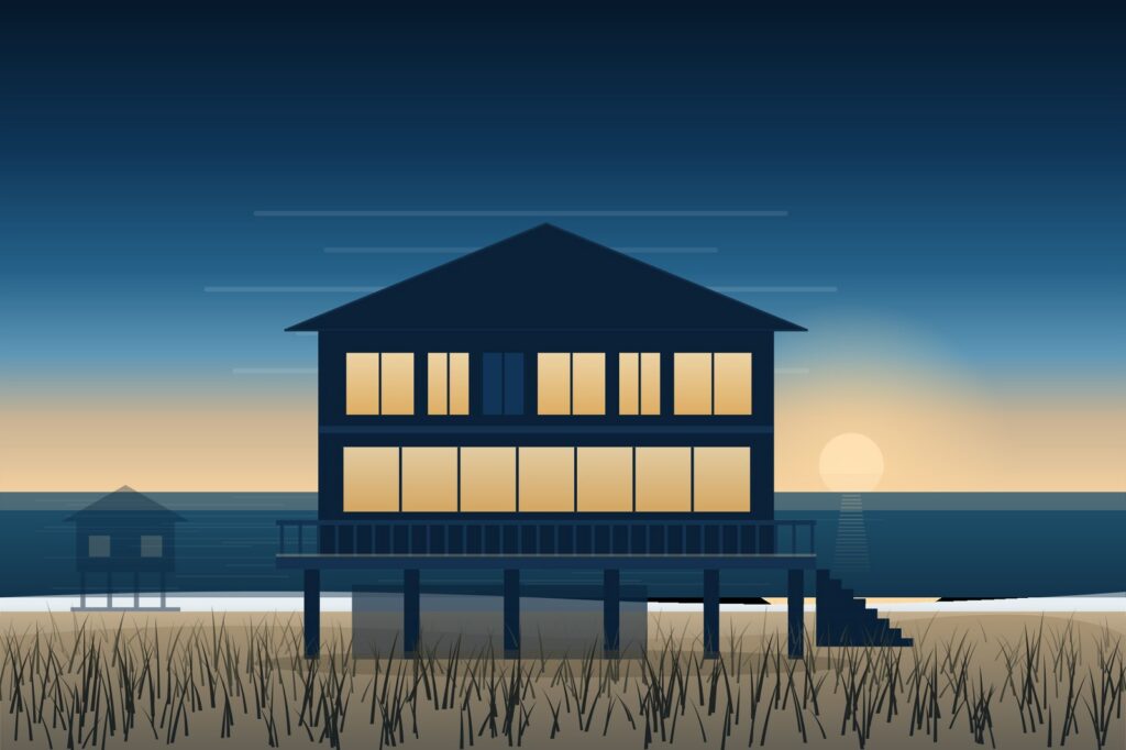 Two-story coastal custom home raised on pilings above a dune at dusk, with lit windows and a wide front deck